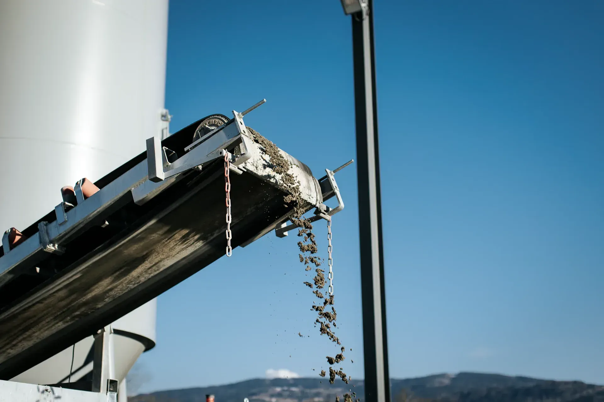 Béton en cours de déversement depuis le tapis du distributeur automatique